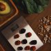 Top view of composed raw almond with seeds and avocado on table with berries on scales for cooking healthy dish